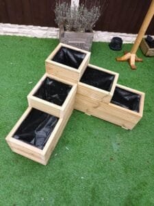 Deep 3-tier L-shaped wooden garden planter on artificial grass with horizontal grooved design