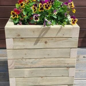 Large Square wooden garden planter filled with vibrant flowers, set against a rustic backdrop